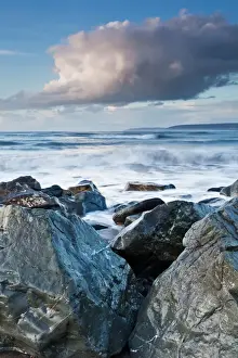 Defence Prints: Large boulders of sea defences at bottom of pebble ridge with waves from incoming tide