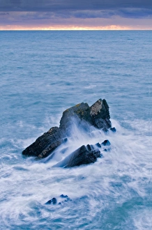 Storm Prints: Large rock lashed by waves in stormy sea at sunset