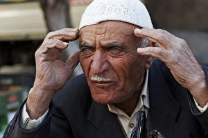 Hand Prints: Market vendor, man holding hands to head, Amman, Jordan, november