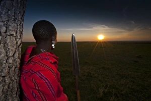 Tribes Prints: Masai tribesman with spear, looking over grassland at sunset, Masai Mara, Kenya