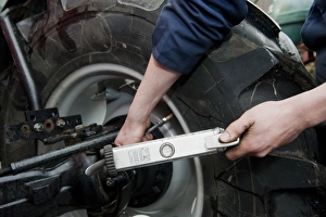 Mechanic checking tyre pressure in tractor tyres, England, october