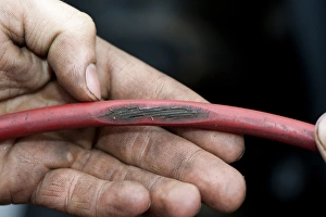 Dangerous Prints: Mechanic with worn cable on tractor which could be dangerous, England, october