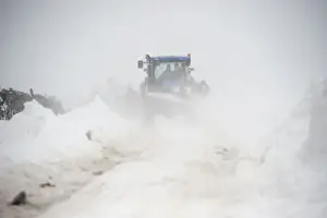 Blizzard Prints: New Holland tractor clearing snow off rural road after snowstorm, Cumbria, England, March