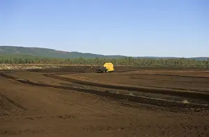 Peat Prints: Peat extraction, tractor pulling mechanical peat extractor, working on peat bog, Sweden