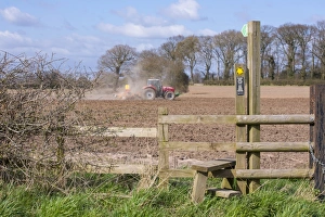 Footpath Prints: Public footpath sign and stile at edge of field, with Massey Ferguson tractor cultivating