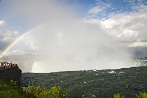 Rainbow forming in spray over waterfall, with tourists on viewing platform, Horseshoe Falls, Niagara Falls