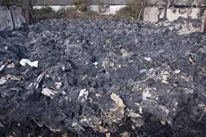 Burning Prints: The remains of burnt straw bales after a Farm barn fire with bits of asbestos roofing mixed with the straw