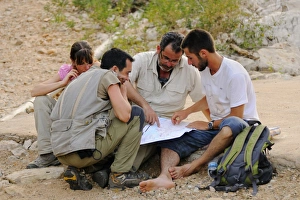 Studying Prints: Researchers looking at map in desert, Socotra, Yemen, march