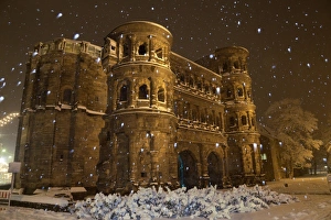 Germany Prints: Roman city gate illuminated during snowfall at night