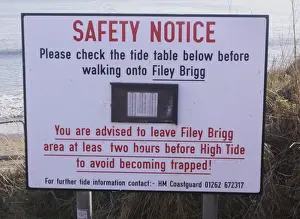 Dangerous Prints: Safety Notice, Please check the tide table below before walking onto Filey Brigg sign on coastal peninsula