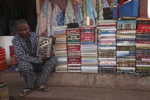 Islam Prints: Salesman selling Koran books in market, Gambia, january