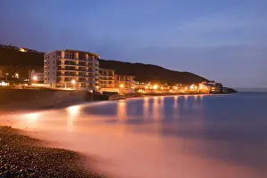 Trending: Sea rushing in over pebbles on beach below promenade in seaside resort before sunrise