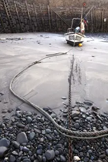 Tides Prints: Small fishing boat on sand, moored in village harbour at low tide