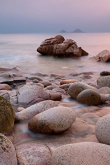 Boulders Prints: Small stream flowing through boulders on beach into sea at sunset
