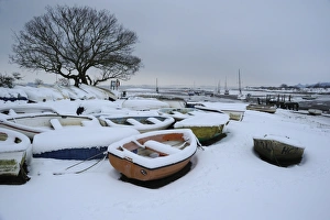 Snow covered boats moored at edge of mudflats, Holbrook Creek, River Stour, Stour Estuary, Lower Holbrook