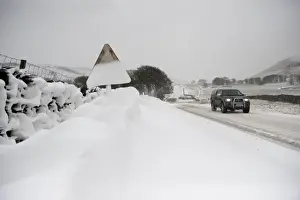 Cars Prints: Snow covered roadsign and vehicle travelling along rural road after snowstorm