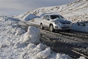 Cars Prints: Snow and slush covered road with car on moorland