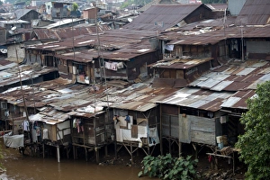 Stilted shacks with corrugated iron roofs beside river in city, Manggarai District, Jakarta, Java, Indonesia, December