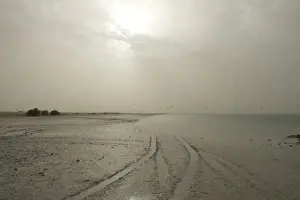 Storm Prints: Sudden sandstorm developing over beach blotting out sun and catching distant kite surfers