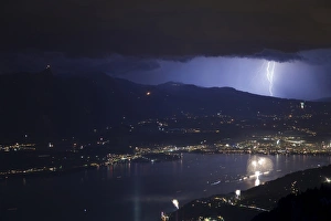 Phenomenon Prints: Thunderstorm with lightning and fireworks over city and lake at night
