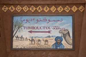 Directions Prints: Tombouctou 52 days direction sign in desert town, Zagora, Sahara, Morocco, may