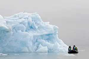 Tourists photographing iceberg from Zodiac inflatable boat, Spitzbergen, Svalbard, july