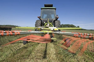 Tractor with Cls Liner 350 rotary rake, turning cut grass for silage crop, Sweden