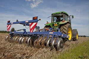 Stubble Prints: Tractor with disc harrows, harrowing stubble field, Sussex, England, september