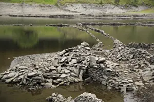 Upland reservoir with low water level and remains of submerged village exposed after dry summer, Mardale Green
