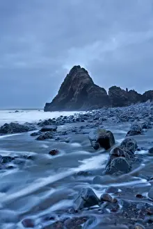 Grey Prints: View of beach and rock formation with receeding tide on overcast evening