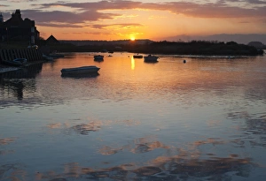 View of boats in coastal creek at high tide, silhouetted at sunset, Burnham Deepdale, Norfolk, England, march