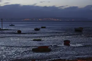View of boats on intertidal mudflats habitat during low tide at night, looking towards Grange-over-sands in Cumbria