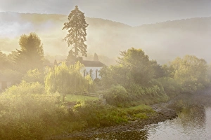 View of church on riverbank in mist at dawn, Moravian Church, Brockweir, River Wye, Forest of Dean, Gloucestershire, England, august