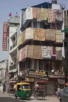 Sub Continent Prints: View of city street with rickshaws, hotels and shop selling rugs, Delhi, India