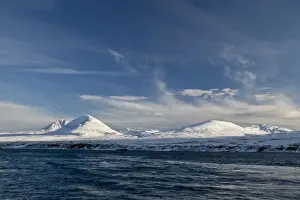 Peak Prints: View of coastline with snow covered mountain peaks in background