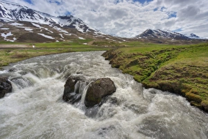 View of fast flowing river with mountains in background, Iceland, June