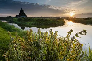 Flood Prints: View of grazing marsh with Stinging Nettle (Urtica (Urtica dioica) patch and church beside flooded ditch at sunset