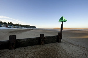 Huts Prints: View of groyne on beach, with distant beach huts in snow