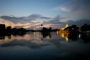 Holy Prints: View of Karaweik (concrete reproduction of royal barge) and Shwedagon Pagoda across lake at sunset