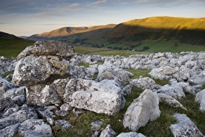 View of limestone pavement at sunrise, Fell End Clouds, looking towards Howgill Fells, Cumbria, England, November