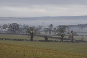 Moor Land Prints: View of mist over fields and farm buildings