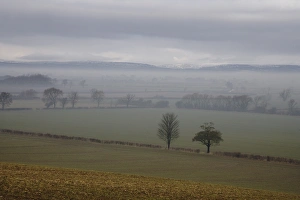 View of mist over fields, with low cloud over moorland in distance, North Yorkshire Moors, near Slingsby