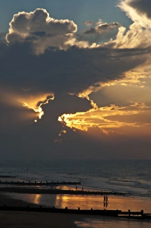 Sun Set Prints: View of people on beach, groynes and clouds at sunset, Cromer, Norfolk, England, July