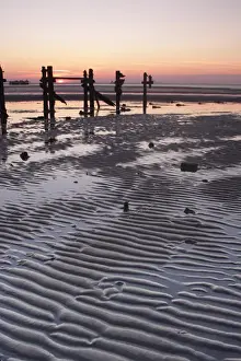 View of ripples in sand and eroded groynes on beach during low tide at sunset, Spurn Point, East Yorkshire, England, october