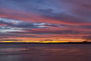 View over river estuary at dawn, with navigation light in foreground, viewed from Beachley looking towards Monmouthshire, River Severn, Severn Estuary, Gloucestershire, England, october