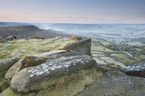 View of rocks and moorland across valley in frost at sunrise, Curbar Gap, Dark Peak, Peak District N. P