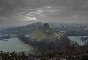 Hilly Prints: View of ruined castle with lights of nearby village at dawn