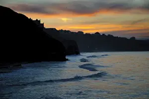 Town Prints: View of sea cliffs and clifftop seaside town silhouetted at sunset