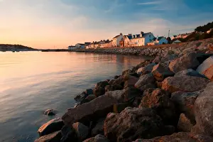 Housing Prints: View of sea wall and houses of seaside village overlooking harbour at sunset