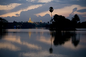 Holy Prints: View of Shwedagon Pagoda across lake at sunset, Kandawgyi Lake, Yangon, Myanmar, March